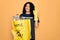 Young african american woman doing volunteering recycling holding bag with plastic bottles doing ok sign with fingers, excellent