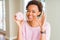 Young african american woman eating pink sugar marshmallows donut doing ok sign with fingers, excellent symbol