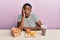 Young african american woman eating a tasty classic burger with fries and soda thinking looking tired and bored with depression