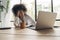 Young african american woman exhausted from studying hard. Bored and frustrated looking at laptop. Head resting on hand.