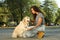 Young African-American woman and her Golden Retriever dog in park