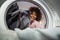 Young African American woman holding a basket of clothes to be washed in a automatic laundry