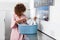 Young African American woman holding a basket of clothes to be washed in a automatic laundry