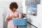 Young African American woman holding a basket of clothes to be washed in a automatic laundry