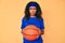 Young african american woman holding basketball ball skeptic and nervous, frowning upset because of problem