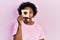 Young african american woman holding bread loaf with heart shape afraid and shocked with surprise and amazed expression, fear and