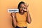 Young african american woman holding comedy word paper smiling happy doing ok sign with hand on eye looking through fingers