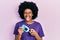 Young african american woman holding glucometer device sticking tongue out happy with funny expression