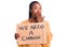 Young african american woman holding we need a change banner covering mouth with hand, shocked and afraid for mistake