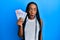 Young african american woman holding swedish krona banknotes scared and amazed with open mouth for surprise, disbelief face