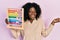 Young african american woman holding traditional abacus screaming proud, celebrating victory and success very excited with raised