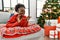 Young african american woman lying on the sofa by christmas tree disgusted expression, displeased and fearful doing disgust face