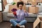 Young african american woman moving to a new home choosing colors smiling happy and positive, thumb up doing excellent and