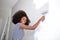 Young african american woman painting wall at home