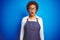 Young african american woman shop owner wearing business apron over blue background afraid and shocked with surprise expression,