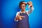 Young african american woman shop owner wearing business apron over blue background smiling making frame with hands and fingers