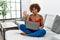 Young african american woman sitting on the sofa at home using laptop showing and pointing up with fingers number five while