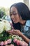 Young african american woman smelling roses in flower shop
