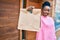 Young african american woman smiling happy holding delivery paper bag with take away food at the city