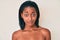 Young african american woman standing topless showing skin relaxed with serious expression on face