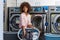 Young African American woman washing her clothes in a automatic laundry