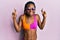 Young african american woman wearing bikini and sunglasses gesturing finger crossed smiling with hope and eyes closed