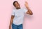 Young african american woman wearing casual white t shirt waiving saying hello happy and smiling, friendly welcome gesture