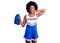 Young african american woman wearing cheerleader uniform holding pompom crazy and scared with hands on head, afraid and surprised