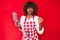 Young african american woman wearing cook apron holding knife annoyed and frustrated shouting with anger, yelling crazy with anger