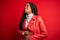 Young african american woman wearing cool fashion leather jacket over red  background with hand on stomach because nausea,
