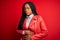 Young african american woman wearing cool fashion leather jacket over red isolated background with hand on stomach because