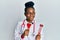 Young african american woman wearing doctor uniform holding tuning fork smiling looking to the side and staring away thinking