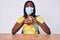 Young african american woman wearing medical mask holding hand sanitizer gel looking at the camera blowing a kiss being lovely and