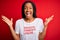 Young african american woman wearing sarcasm coments text on t-shirt over red background very happy and excited, winner expression