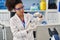 Young african american woman wearing scientist uniform closing bottle at laboratory