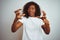 Young african american woman wearing t-shirt standing over isolated white background Shouting frustrated with rage, hands trying