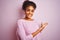 Young african american woman wearing winter sweater standing over isolated pink background Inviting to enter smiling natural with