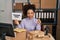 Young african american woman working at small business ecommerce holding thank you banner smiling with an idea or question