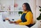 Young african american woman writing notes or filling documents while sitting at the desk at home office