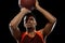 Young african basketball player training on black studio background.