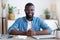 Young african boss smiling and listening attentively while sitting at his desk