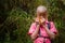 Young African boy with bright pink shirt eating maize comb in front of high tropical reed, Ring Road, Cameroon, Africa