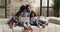 Young African couple little kids relaxing on couch with laptop