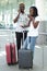 Young african couple talking and checking the smartphone and holding suitcases