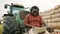 Young african farmer using tablet while sitting on green tractor. Haystack in the background