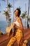 Young african female model posing in colorful clothes at tropical location at sunrise. Black woman against exotic
