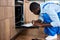 Young African Handyman Writing Information About Electric Oven Before Repair