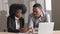 Young African male mentor trainer coach in suit showing computer software to new female worker learning skills in office