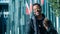 Young African man in a black outfit walking in a street posing in front of a glass paneled building