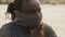 Young african man with braided hair covering nose and mouth with roller neck sweater